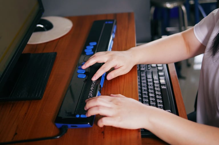 Person with blindness disability's hands using computer with braille display or braille terminal a technology assistive device