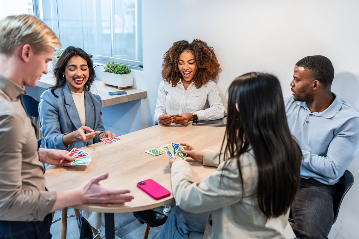 Multi-ethnic coworkers enjoying a break from work, playing cards and having fun together in a modern office