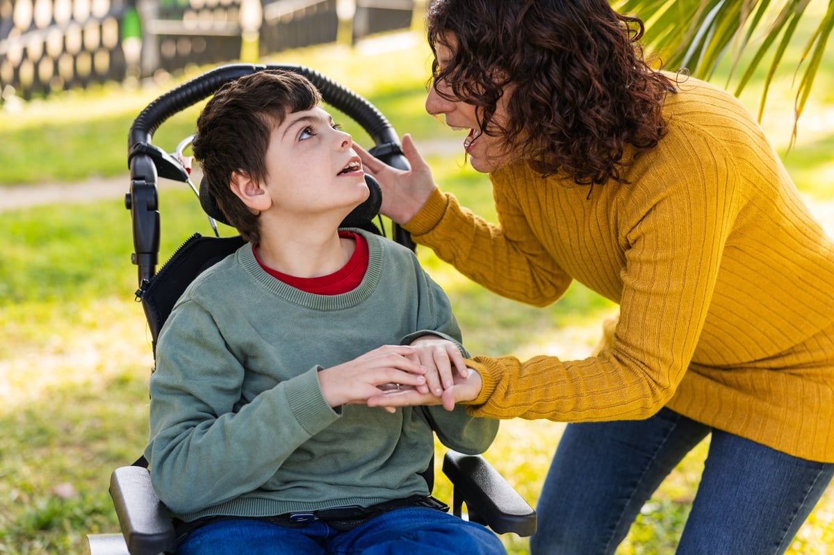 Loving mother supporting her son with disability providing care and affection in a heartwarming outdoor setting