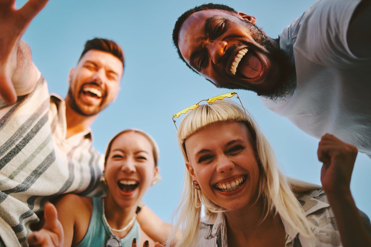 Four cheerful multi-ethnic friends are having fun together outdoors laughing and enjoying their time
