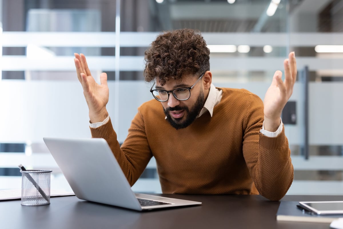 A person at his desk, visibly frustrated while confronting an interface that should work for him but does not