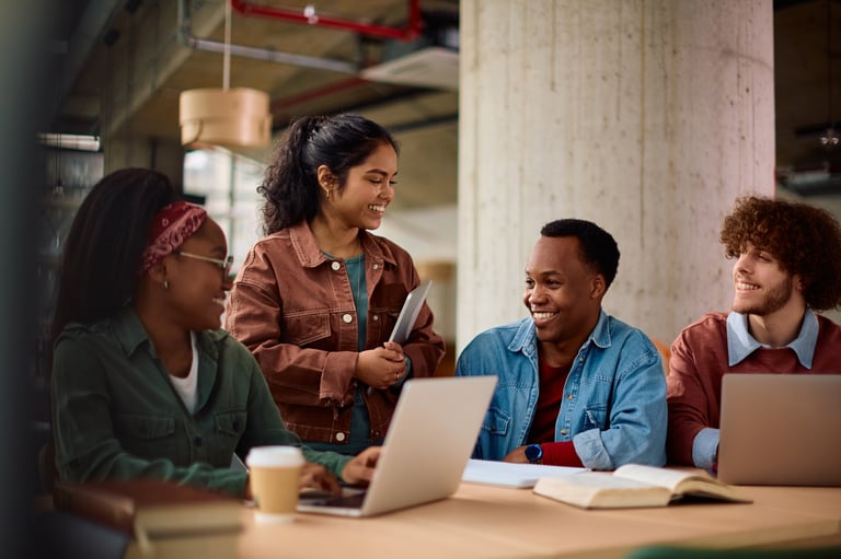 Multiracial group of happy college friends cooperating while studying at campus